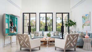 A modern living room with a teal bookshelf, a light blue sofa set, and a coffee table. - Port Royal - Sweeping Lake Views (Naples)