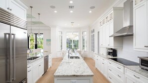 A modern kitchen with white cabinetry, stainless steel appliances, and a central island. - Port Royal - Sweeping Lake Views (Naples)