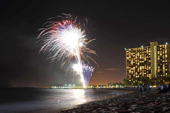 Un hôtel en bord de mer offrant une vue sur les feux d’artifice tirés au-dessus de l’eau.