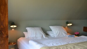 A neatly made bed with white linens and pillows, two wall-mounted lamps, and a small nightstand with a vase of flowers. - Double room in the Gasthaus am Finowkanal (former school from 1875). (Wandlitz)