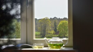 A view through a window with a book and a glass container on a table. - Double room in the Gasthaus am Finowkanal (former school from 1875). (Wandlitz)