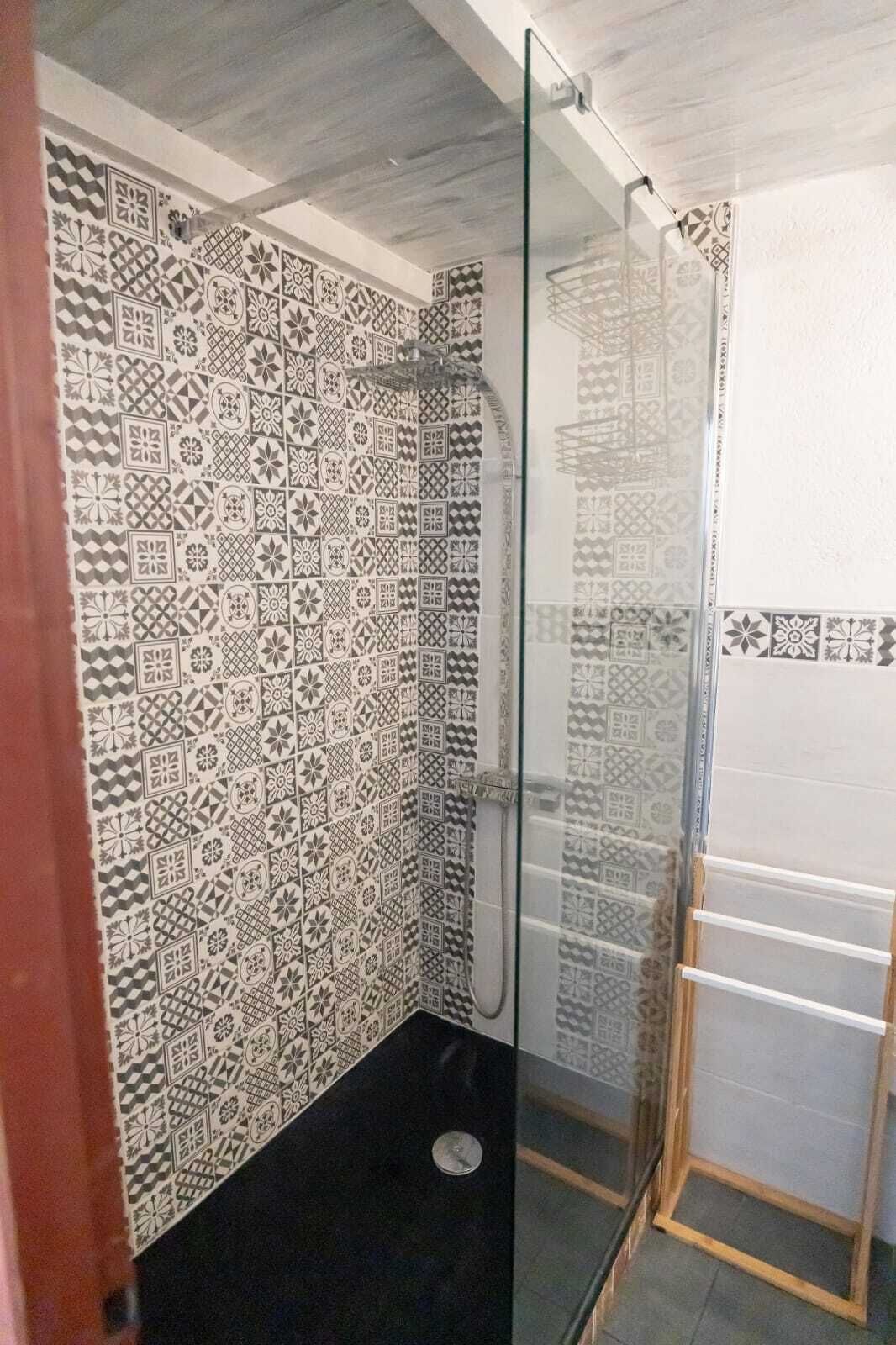 A shower with patterned tiles and a glass door.