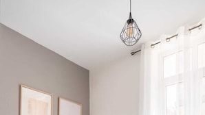 A bedroom with a bed, a nightstand, a lamp, and a window with curtains. - Downtown Apartment ° 2 bedrooms ° near the Arènes ° air conditioning  (Nîmes)