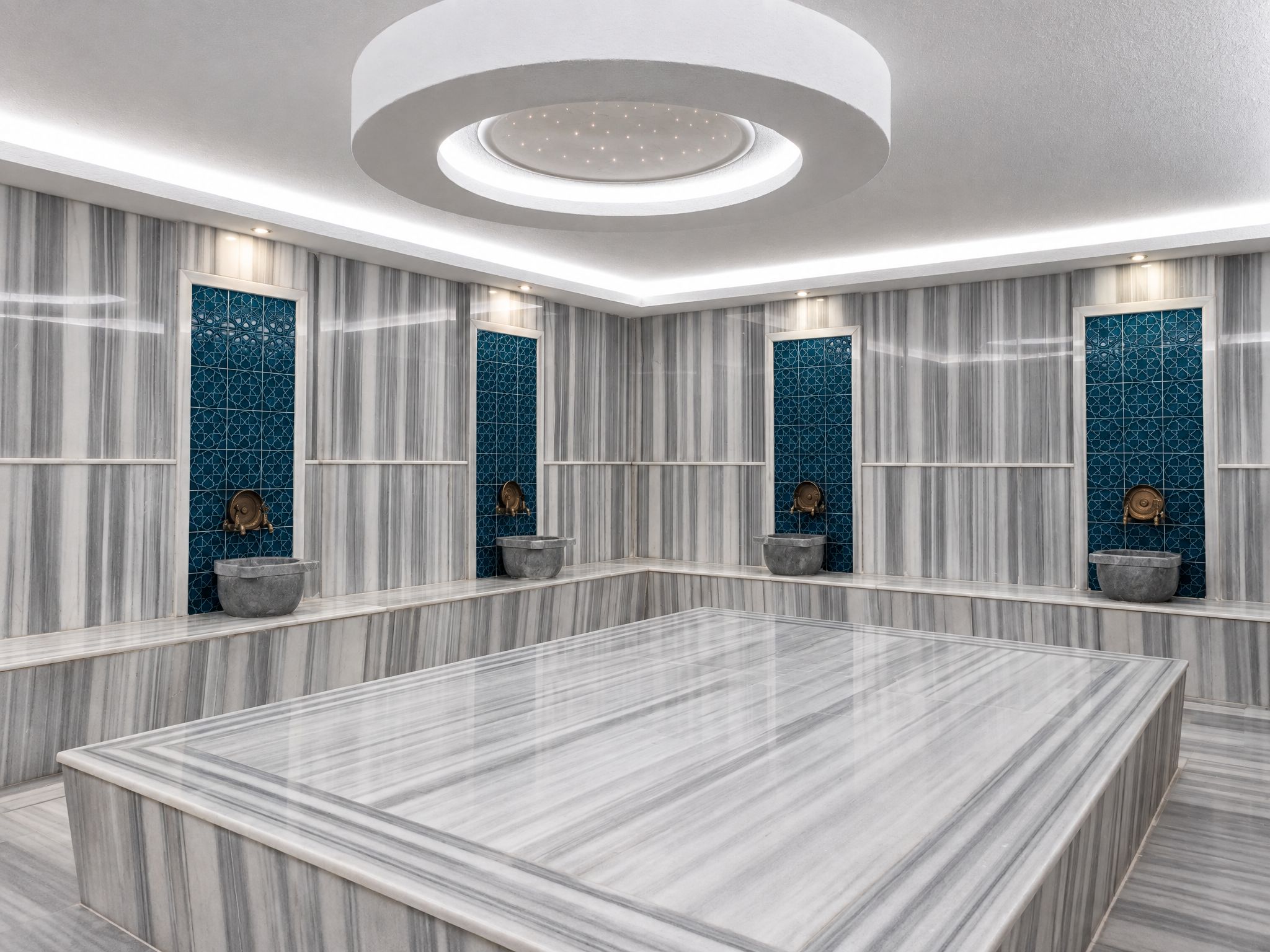 Un baño moderno con un amplio tocador de mármol, una lámpara de techo circular y azulejos decorativos.