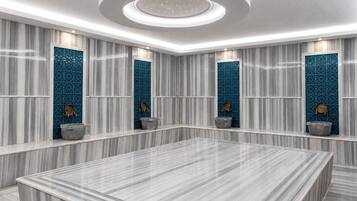 Un baño moderno con un amplio tocador de mármol, una lámpara de techo circular y azulejos decorativos.