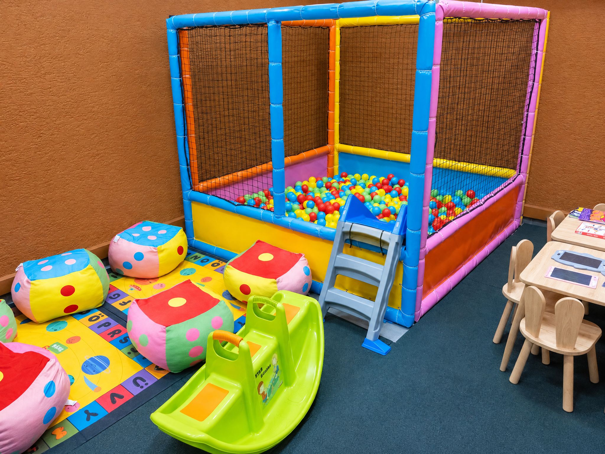 A children's play area with a ball pit, soft play structures, and a small slide.