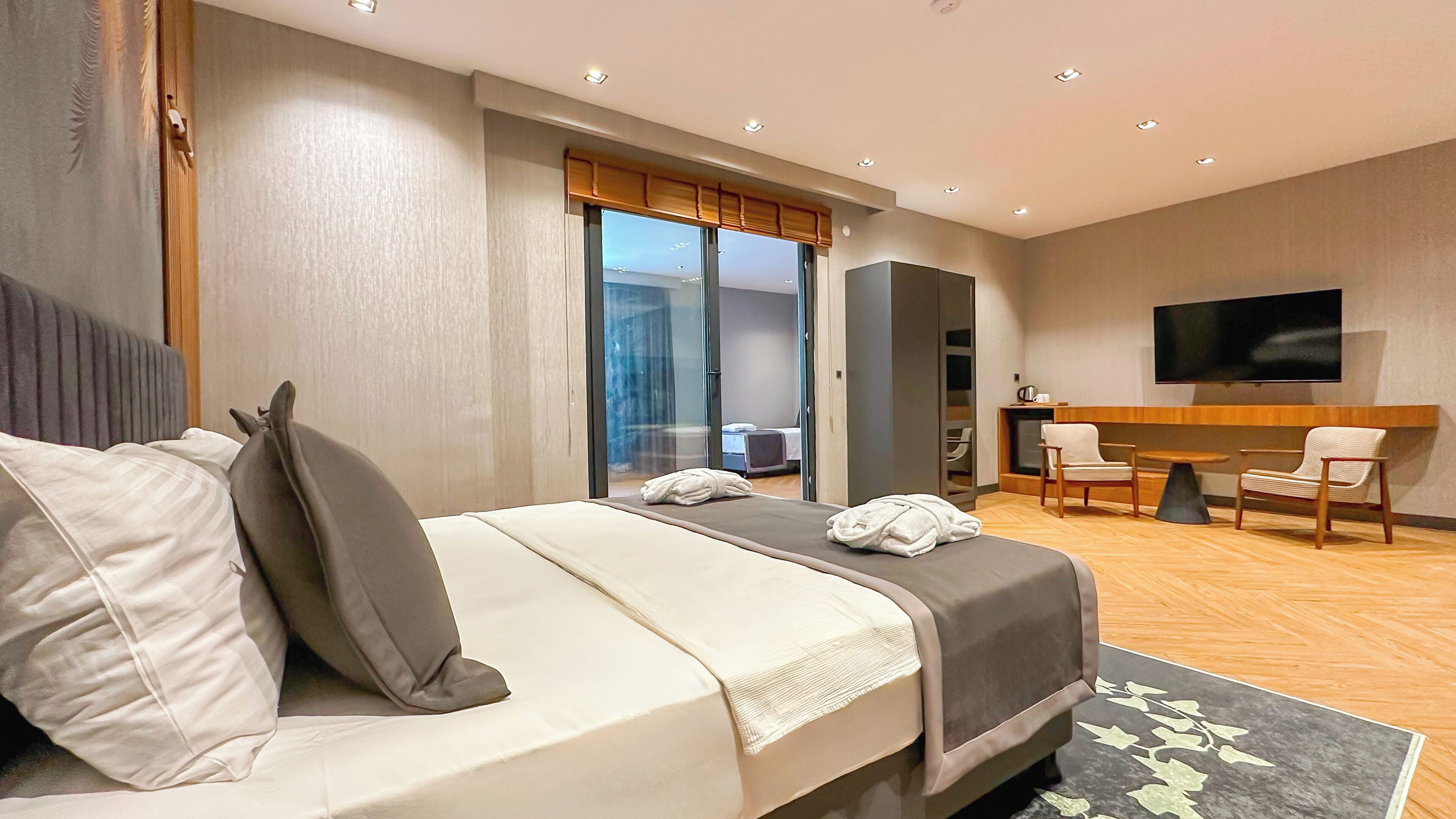 Una habitación de hotel moderna con una cama grande, un escritorio, una silla y un televisor.