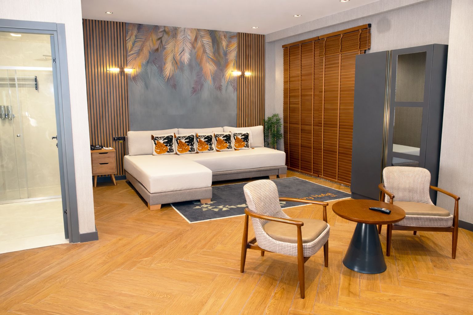 A modern bedroom with a sofa bed, two armchairs, a small table, and a large mirror.