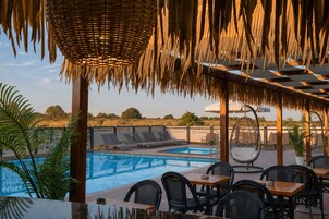 Un área junto a la piscina con sillones de descanso, una mesa de comedor y un sillón colgante.