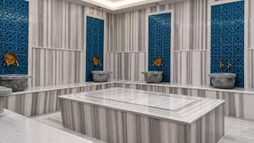 A modern bathroom with marble flooring, a central heated marble bench, and decorative blue tiles on the walls.