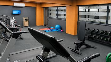A gym with exercise equipment, a television, and a window with exercise illustrations.