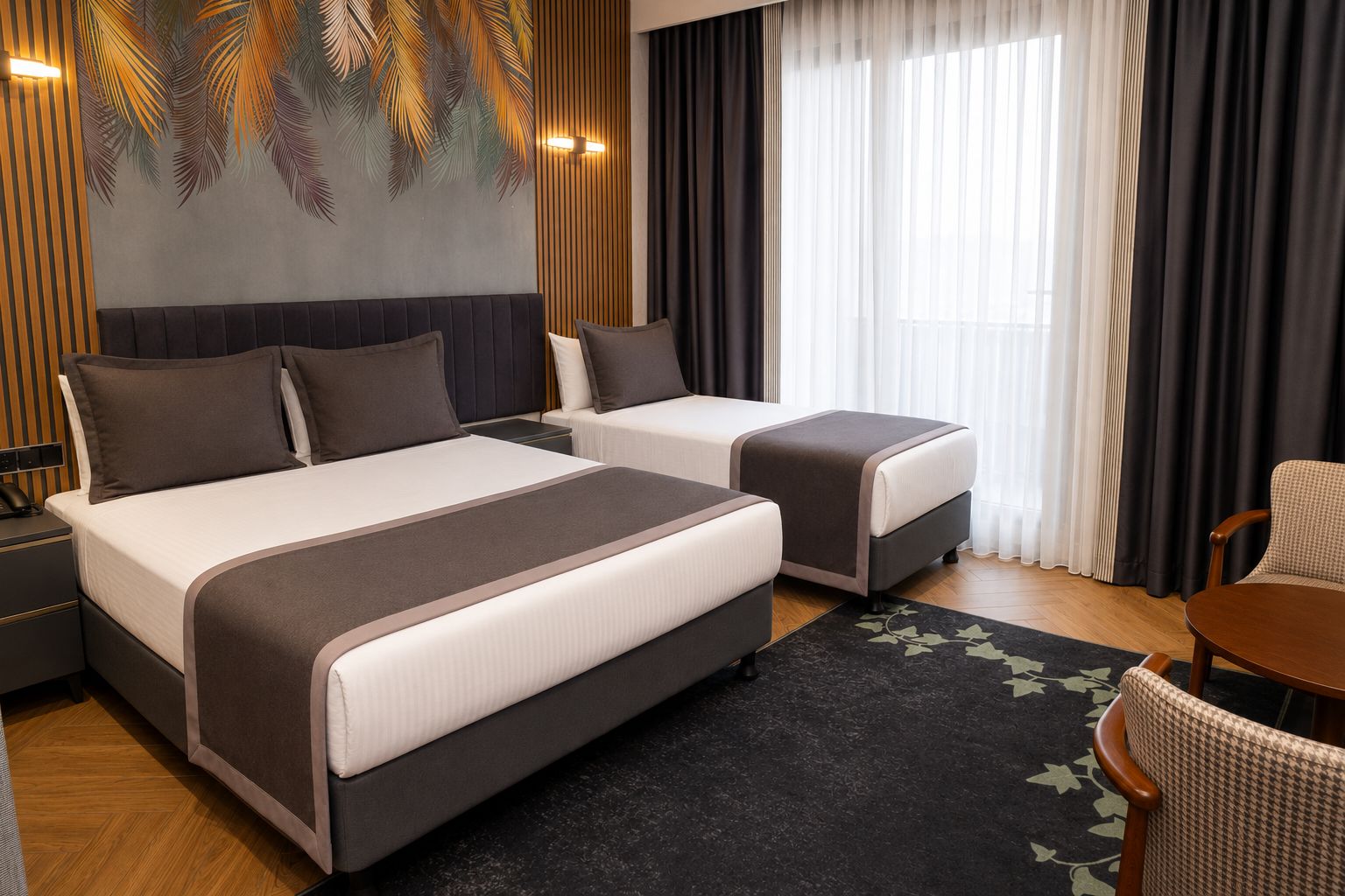 Une chambre d’hôtel avec deux lits, une grande fenêtre avec des rideaux, un lampadaire fixé au mur et une petite table avec une chaise.