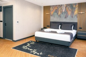 Habitación de hotel con cama, mesitas de noche, luz empotrada en la pared, una puerta y una alfombra estampada.