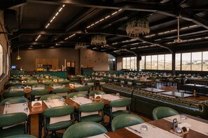 A restaurant with multiple dining tables and booths, a kitchen area, and a view of the outdoors. - ivy Hotel Spa (Cinarcik)