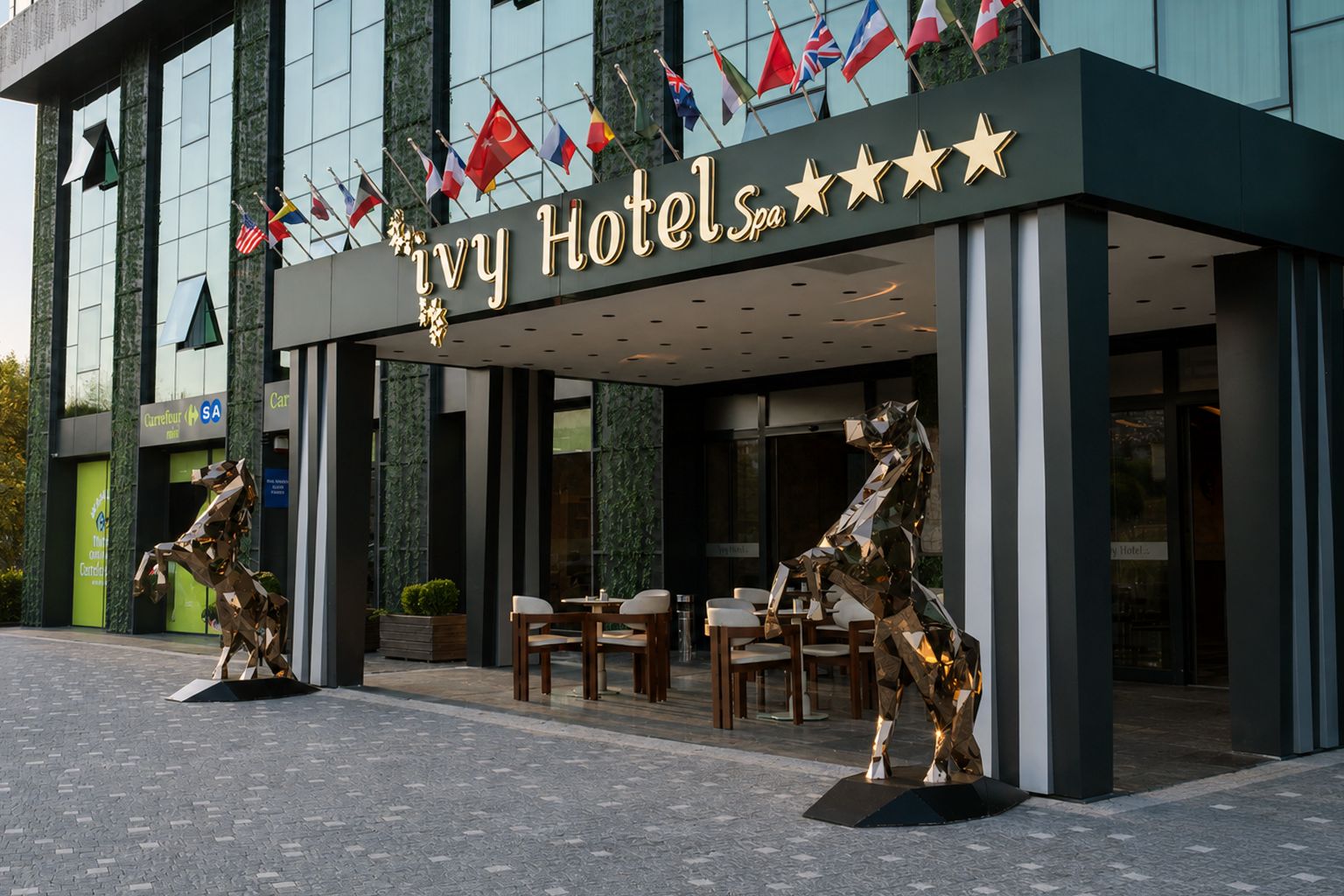 Die Fassade des Ivy Hotels mit modernem Design, einschließlich eines markanten Eingangs und zwei Pferdestatuen.