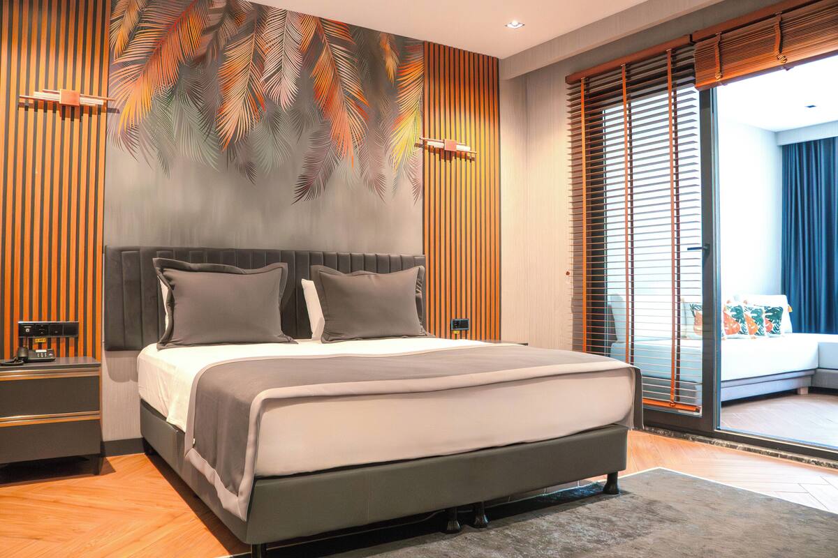 A modern bedroom with a large bed, wooden panel walls, and a view to the outside.