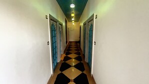 A hallway with a checkered floor, blue doors, and a light fixture on the ceiling. - Aaj Haveli - A Luxury Boutique Hotel (Udaipur)