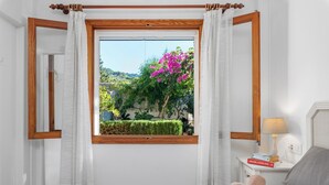 A bedroom with a large window, a bedside table with a lamp, and a bed with towels. - Apartment Bougainvillea,  a beautiful apartment just a few steps from the beach. (Port de Sóller)