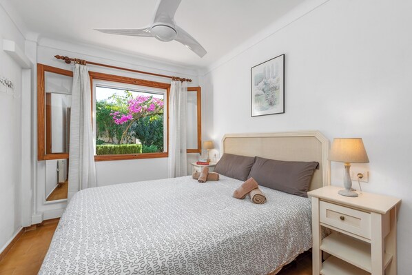 Une chambre à coucher avec un lit, une table de chevet, une lampe et une fenêtre avec des rideaux.