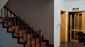 Una escalera de madera con balaustres y peldaños oscuros que conduce a una plataforma.