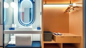 Un baño moderno con un espejo redondo, un lavabo y un mueble de tocador de madera con un perchero para toallas.