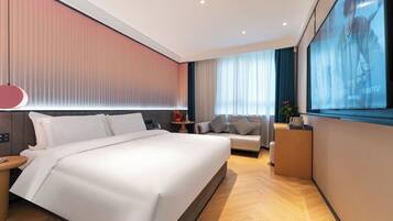 Een moderne hotelkamer met een groot bed, een bank, een televisie en een bureau.