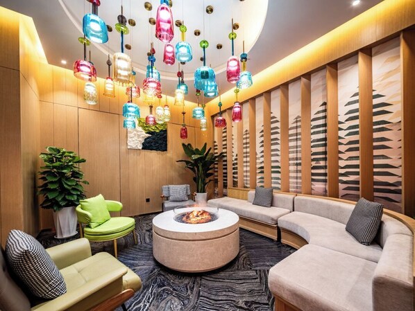 A modern lounge area with a round coffee table, sofas, and colorful hanging lights. - SHUYU HOTEL (Xi'an)