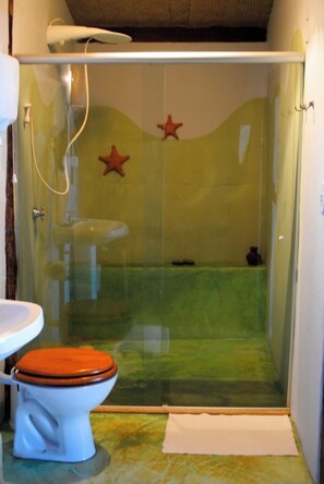 A bathroom with a glass-enclosed shower, a toilet with a wooden seat, and a sink. - Pousada Shangri-lá (Itacaré)