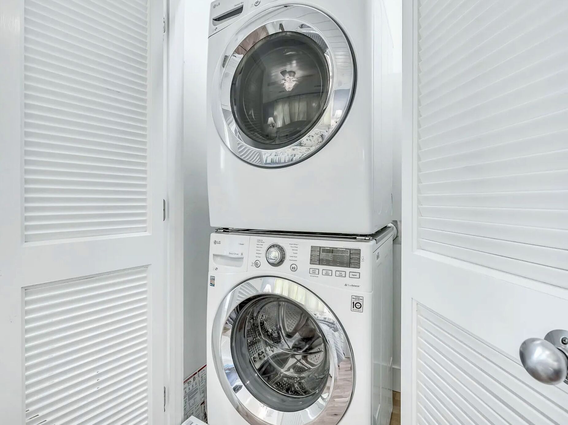 Een gestapelde wasmachine en droger in een witte ruimte.
