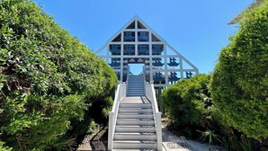 A staircase leading to a modern building with a triangular roof and multiple windows. - Amazing Porches, Outdoor Dining, & Tower in Seaside, FL! 2 Kings! 2 Bikes! (Santa Rosa Beach)