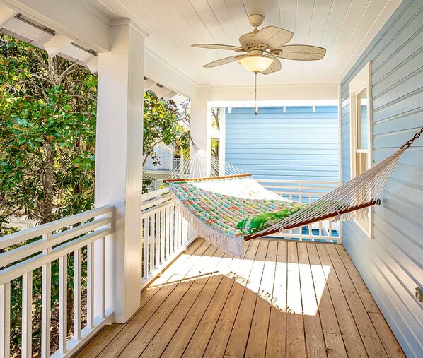 A wooden deck with a hammock, white railings, and a ceiling fan. - Amazing Porches, Outdoor Dining, & Tower in Seaside, FL! 2 Kings! 2 Bikes! (Santa Rosa Beach)