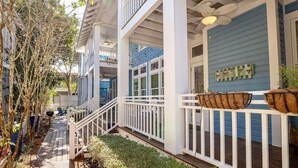 A multi-story building with white railings, a covered porch, and a blue exterior wall. - Amazing Porches, Outdoor Dining, & Tower in Seaside, FL! 2 Kings! 2 Bikes! (Santa Rosa Beach)