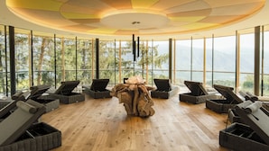 A sun lounge area with large windows and a wooden floor. - Hotel Der Waldhof in Völlan (Lana)