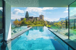 A modern pool with a clear view of a historic castle in the background. - Hotel Der Waldhof in Völlan (Lana)