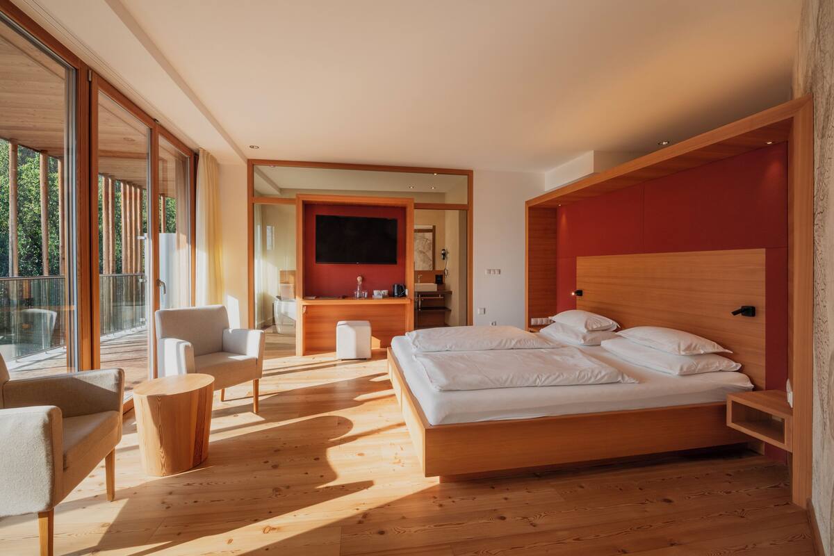 A modern bedroom with a large bed, a desk, and a chair.