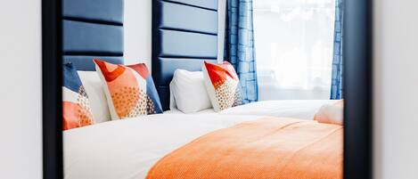 A modern bedroom with a large bed, a headboard, and a window with curtains.