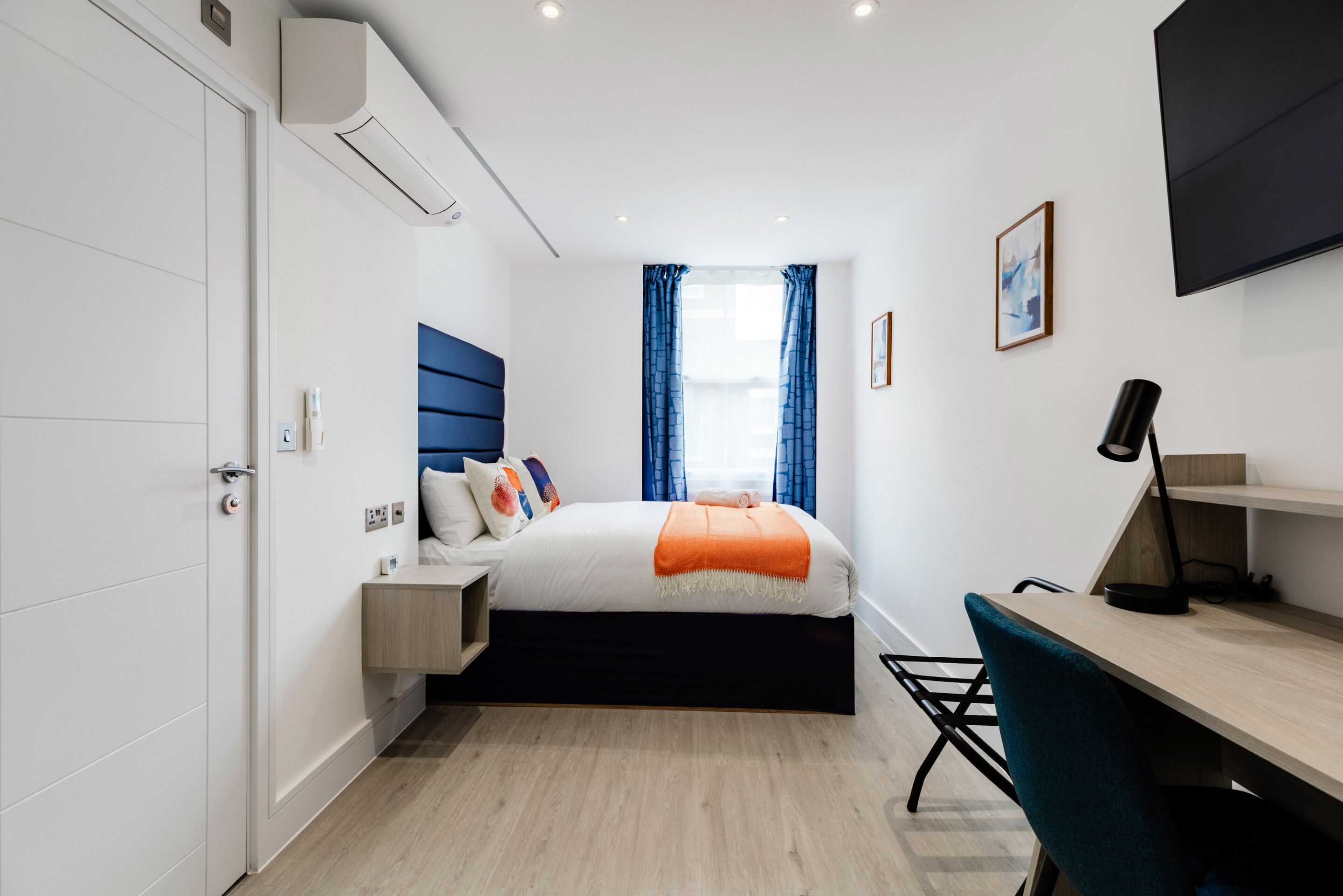 A modern bedroom with a bed, bedside table, and a desk with a chair.