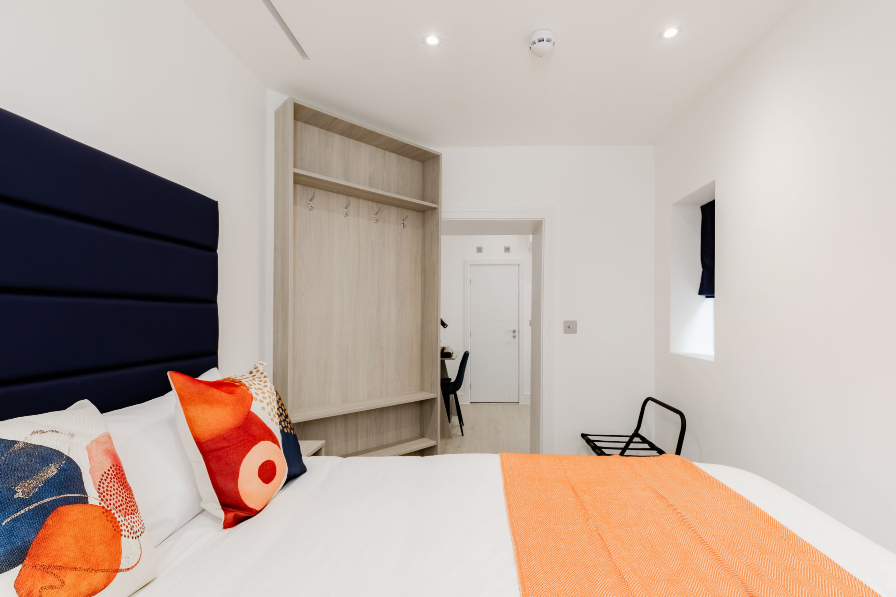 Een moderne slaapkamer met een groot bed, een kledingkast en een bureau.
