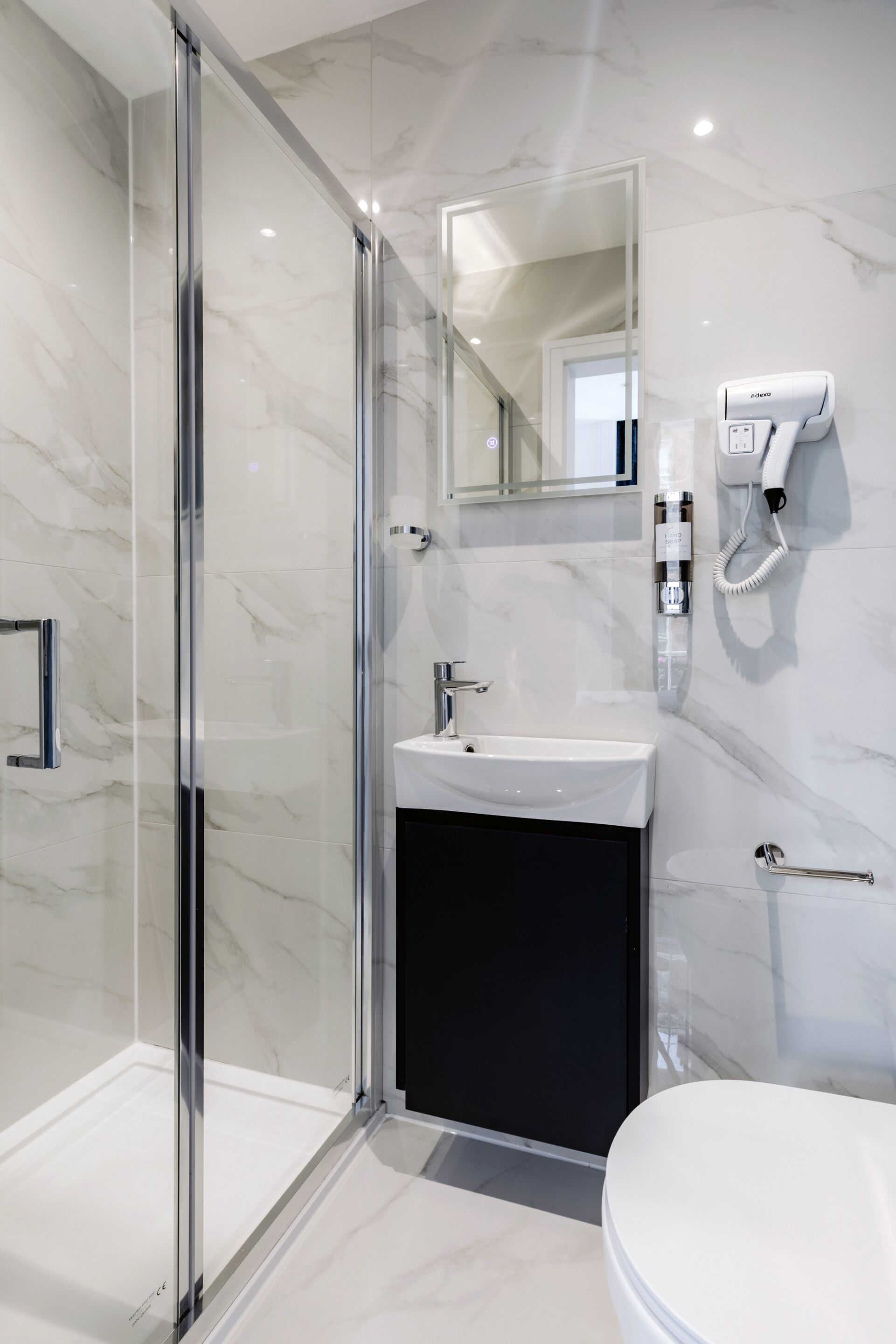 A modern bathroom with a glass shower enclosure, a white sink, and a toilet.