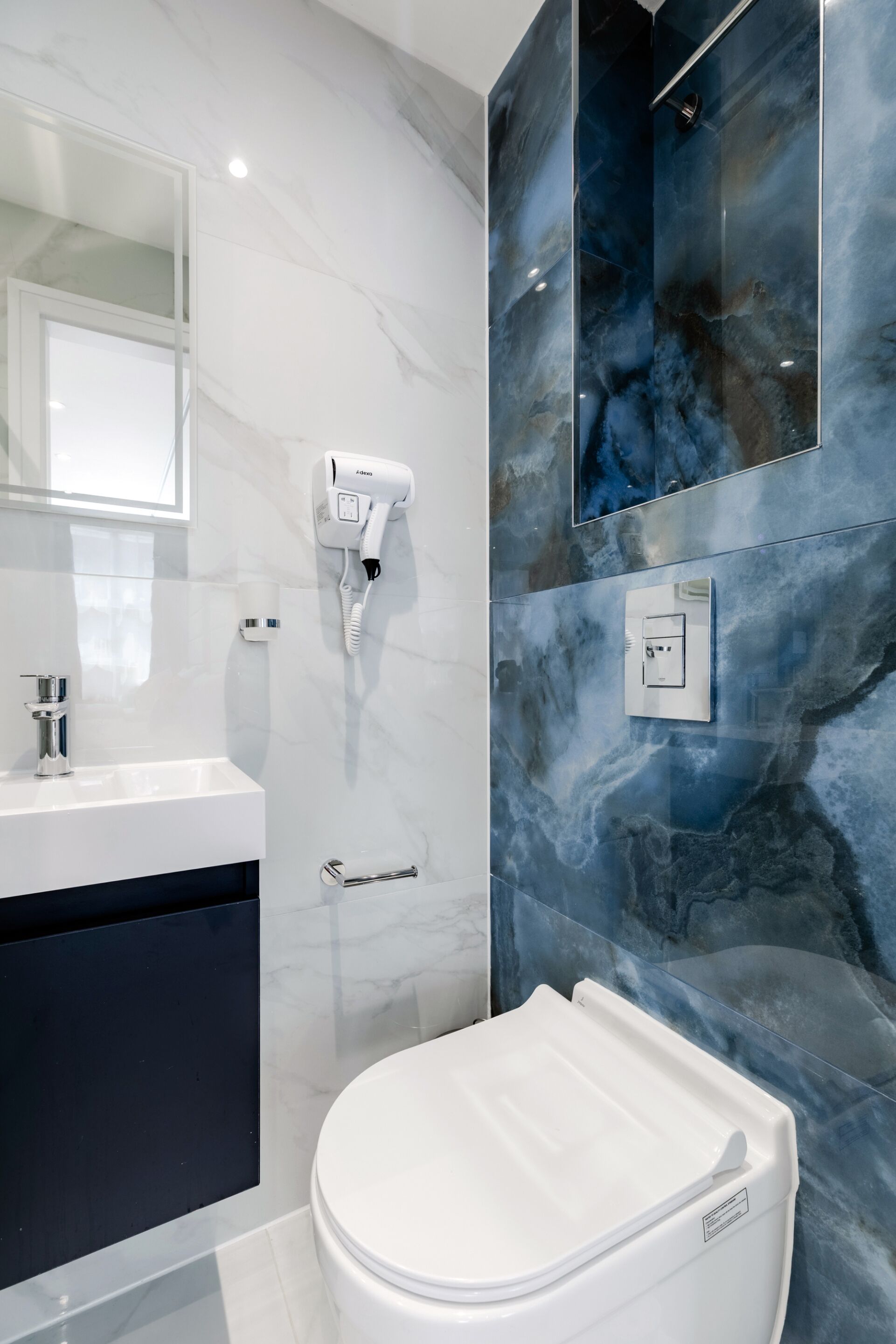 Un baño moderno con inodoro blanco, tocador con espejo y zona de ducha con puerta de cristal.