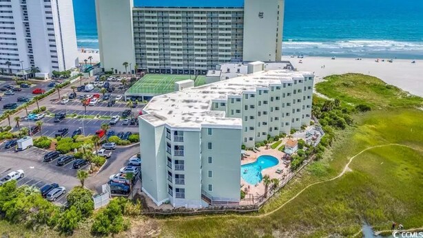 A hotel with a swimming pool, parking lot, and beachfront view. - Cozy Beach living with Breathtaking Ocean and Marsh Views, Sleep 4 (Myrtle Beach)