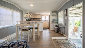 A compact kitchen with a dining area, a small island, and a view of the outdoors through a sliding door. - 2 BR@Peachtree, Walk2Sand + Sit by Water (Ocean City)