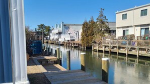 A wooden dock extending into a calm waterway with buildings in the background. - 2 BR@Peachtree, Walk2Sand + Sit by Water (Ocean City)