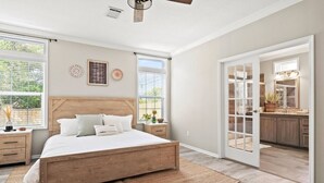 Une chambre à coucher avec un lit en bois, des tables de chevet et une grande fenêtre.