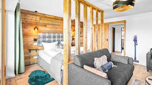 A modern bedroom with a wooden headboard, a grey sofa, and a blue vacuum cleaner. - Atelier Wilder Kaiser | Pool, sauna & mountain view (Reit im Winkl)