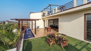 Une maison moderne dotée d’une piscine, d’un espace salon extérieur et offrant une vue sur le paysage.