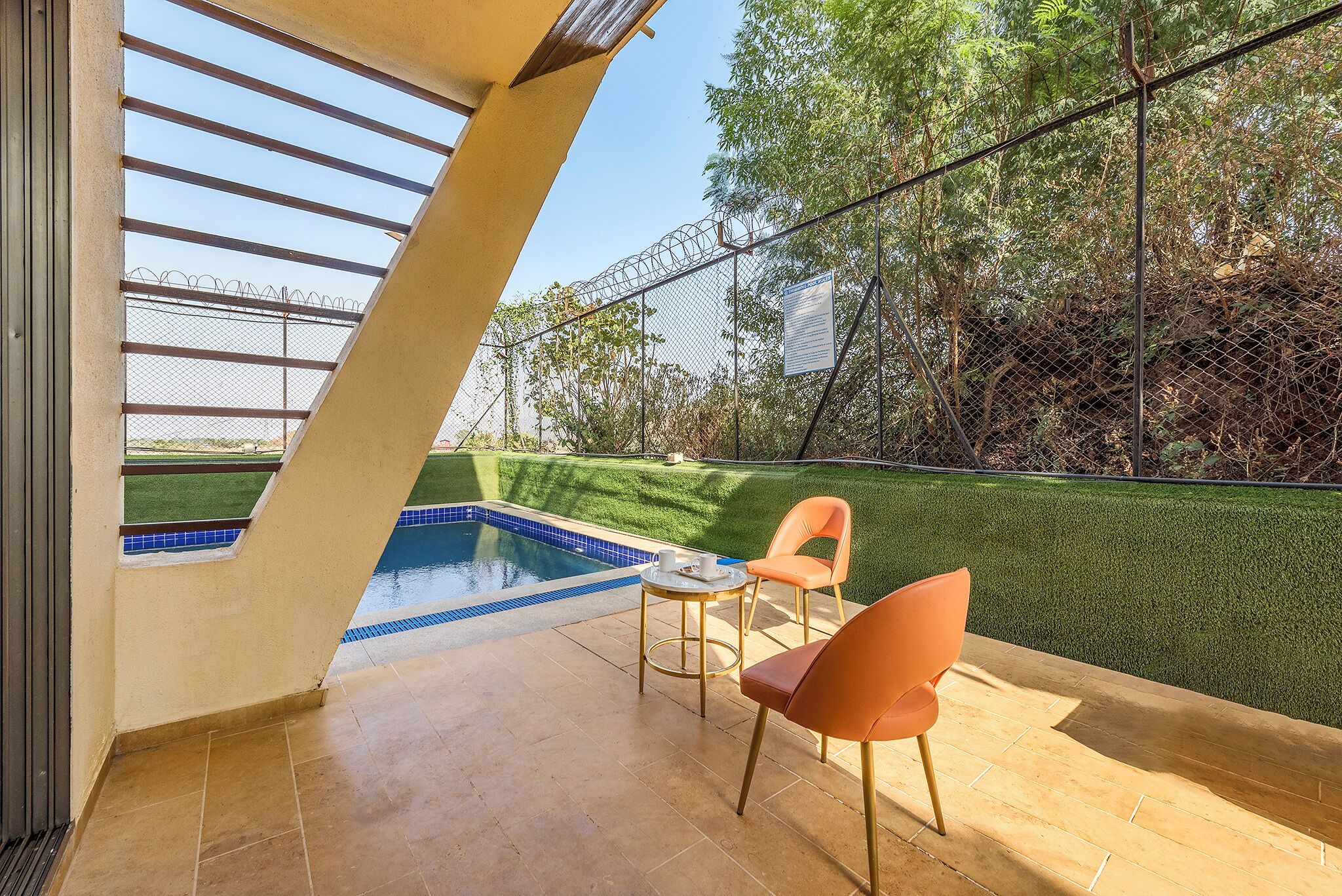 A pool area with a clear view of the pool, a chair, and a table.