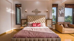 Une chambre spacieuse avec un grand lit, un canapé et une vue sur l’extérieur.