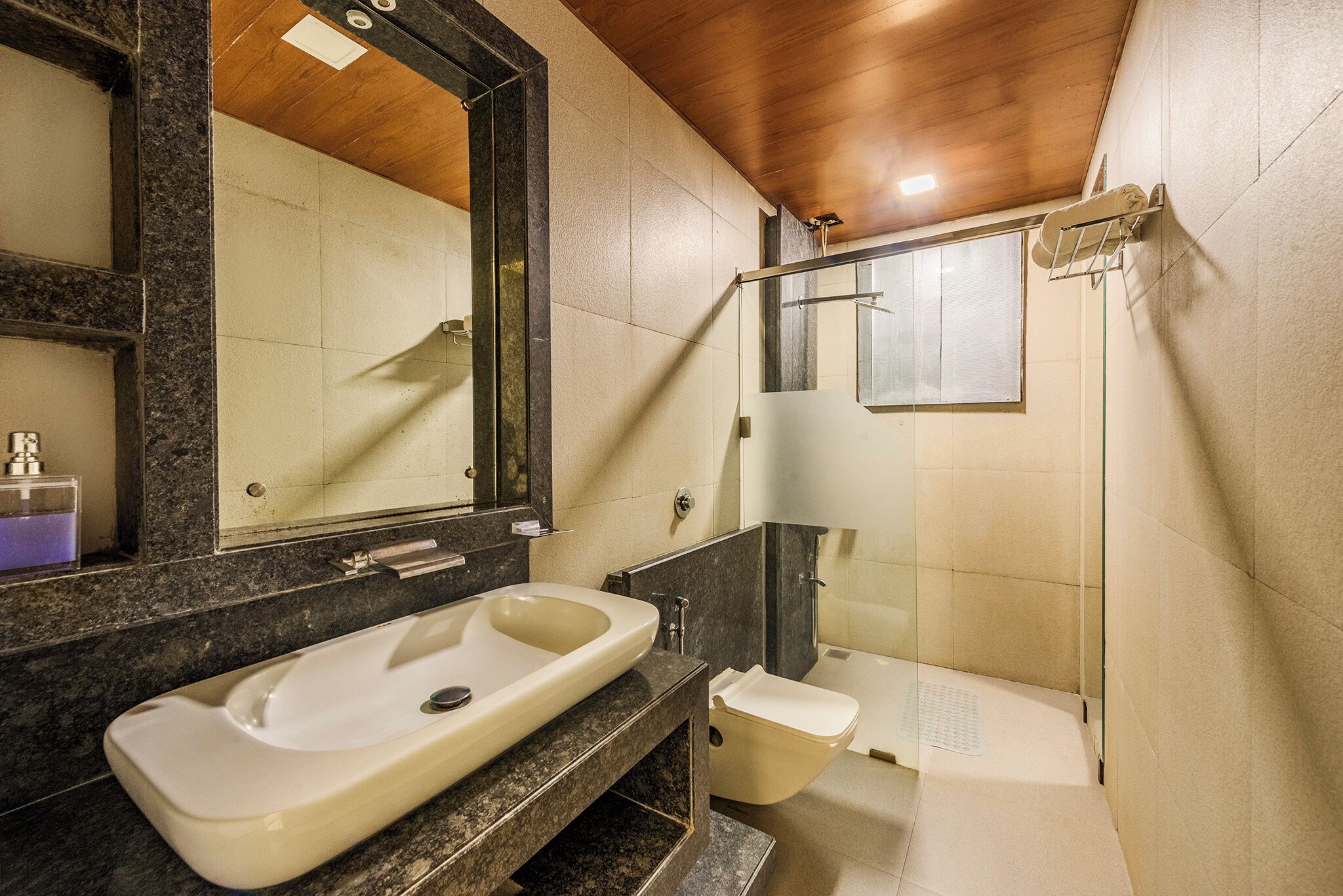 Un bagno moderno con un lavandino capiente, il water e una doccia.
