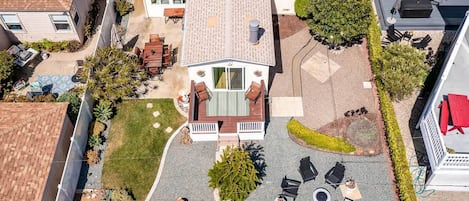 An aerial view of a residential property with a patio, outdoor seating, and a small garden area.
